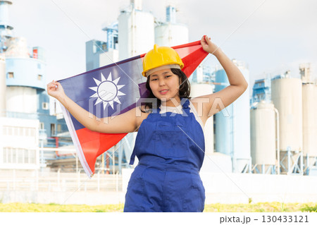 Happy asian girl in work clothes and hardhat with flag of taiwan standing in front of industrial scenery Happy asian girl in work clothes and hardhat with flag of taiwan standing in front of industrial scenery 130433121