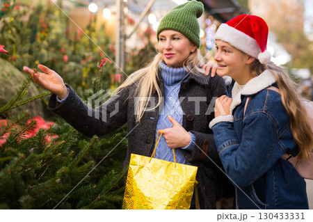 Mother with teenager daughter choose christmas tree at street fair 130433331