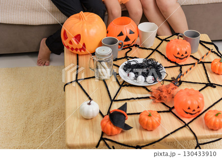 A table is decorated for a fun halloween day celebration, pumpkins and a spider web decorate the table for parties for children and adults at home. 130433910