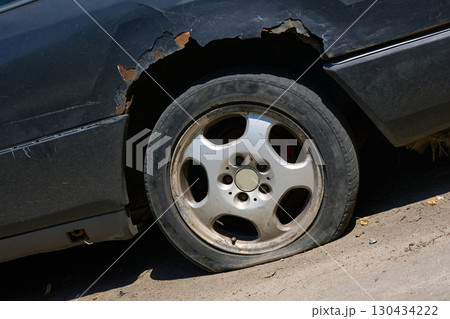 Old messy car with a rusty wing,a flat tire 130434222