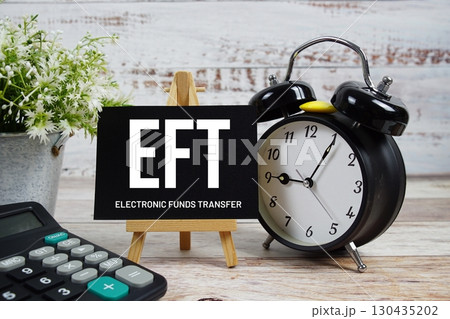 EFT Electronic Funds Transfer text with alarm clock and calculator on wooden background EFT Electronic Funds Transfer text with alarm clock and calculator on wooden background 130435202