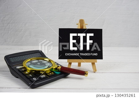 ETF abbreviation of Exchange Traded Fund text with magnifying glass and calculator on wooden background ETF abbreviation of Exchange Traded Fund text with magnifying glass and calculator on wooden background 130435261