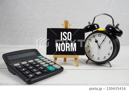 ISO NORM text with alarm clock on wooden background 130435416