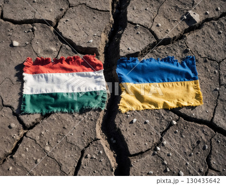 tattered flags of ukraine and hungary against cracked earth, concept of political crisis 130435642