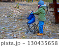 An independent child unfolds a folding chair at a autumn picnic 130435658