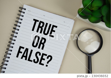 True or False? text on paper notebook with magnifying glass on beige leather background 130436032