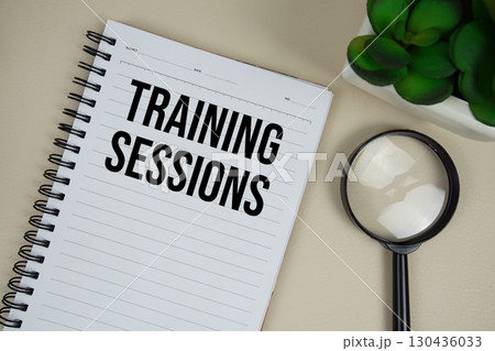 Training Sessions text on paper notebook with magnifying glass on beige leather background Training Sessions text on paper notebook with magnifying glass on beige leather background 130436033
