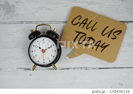 Call Us Today text with alarm clock on wooden background 130436138