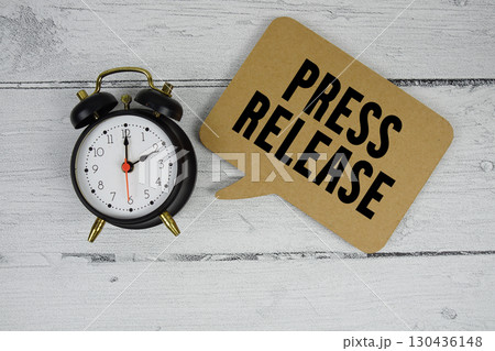 Press release text with alarm clock on wooden background Press release text with alarm clock on wooden background 130436148