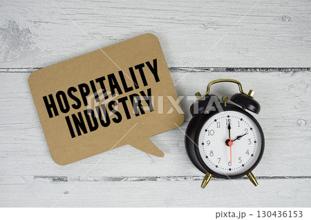 Hospitality industry text with alarm clock on wooden background 130436153