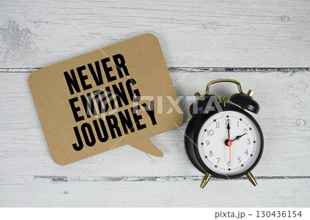 Never ending journey text with alarm clock on wooden background 130436154