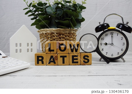 LOW RATES alphabet letters with house model, alarm clock and magnifying glass on wooden background 130436170