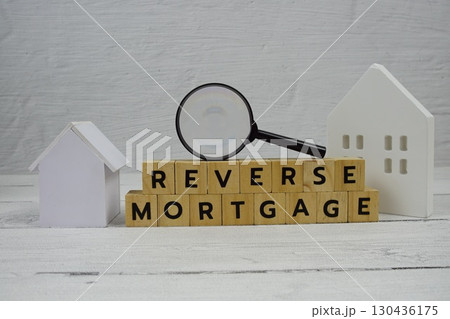 Reverse Mortgage alphabet letters with house model and magnifying glass on wooden background 130436175