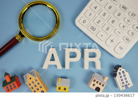 APR abbreviation of Annual Percentage Rate alphabet letters with house model, magnifying glass and calculator on blue background 130436617