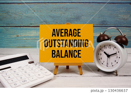 Average Outstanding Balance text written on paper card with calculator and alarm clock on wooden background Average Outstanding Balance text written on paper card with calculator and alarm clock on wooden background 130436637