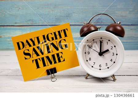 Daylight Saving Time  text written on paper card with alarm clock on wooden background 130436661