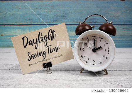 Daylight Saving Time text written on paper card with alarm clock on wooden background Daylight Saving Time text written on paper card with alarm clock on wooden background 130436663