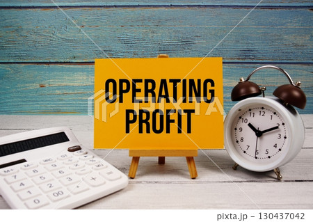 Operating Profit text written on paper card with calculator and alarm clock on wooden background Operating Profit text written on paper card with calculator and alarm clock on wooden background 130437042