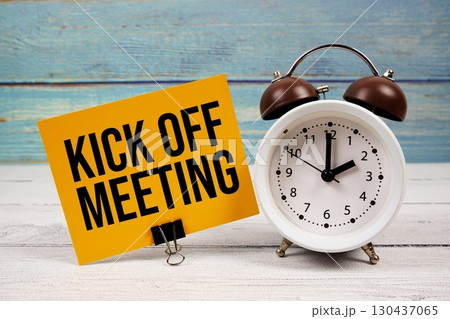 Kick Off Meeting text written on paper card with alarm clock on wooden background Kick Off Meeting text written on paper card with alarm clock on wooden background 130437065