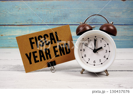 Fiscal Year End text written on paper card with alarm clock on wooden background 130437076