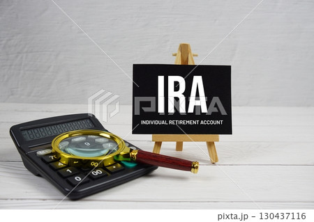 IRA abbreviation of Individual Retirement Account text with magnifying glass and calculator on wooden background IRA abbreviation of Individual Retirement Account text with magnifying glass and calculator on wooden background 130437116