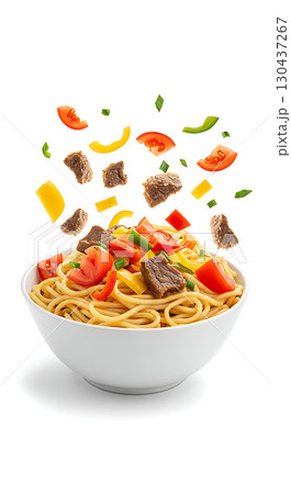 A white bowl filled with spaghetti, topped with chunks of beef, tomato slices, yellow bell pepper, and green onions. Ingredients appear to be floating above the bowl 130437267