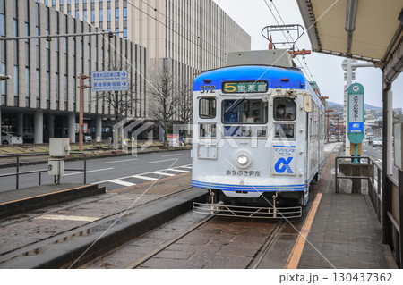 March 28 2025 Tram at a Station Stop in an Urban City Street Environment, Japan March 28 2025 Tram at a Station Stop in an Urban City Street Environment, Japan 130437362