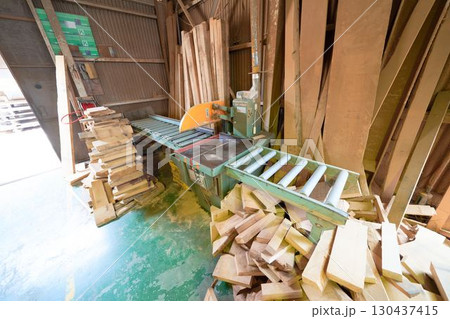 木工所に設置された横切り盤と積み上げられた木材 130437415