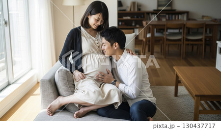 ソファでお腹をさする妊娠中の妻を優しく見守る夫 130437717