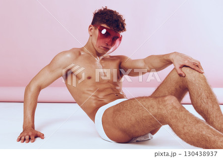 Confident young man posing in trendy pink sunglasses, showcasing a modern fashion style. Fashion and self-expression concept with vibrant backdrop. Confident young man posing in trendy pink sunglasses, showcasing a modern fashion style. Fashion and self-expression concept with vibrant backdrop. 130438937