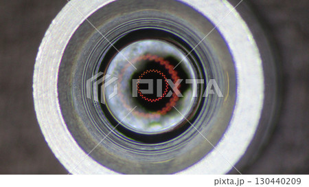 Mysterious macro closeup of an optic lens inside metal tube. This abstract camera technology shows futuristic view with an intriguing red circle and precise focus 130440209