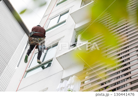 Exterior paint and leak repair technician builder, rope rappelling to repair buildings outside wall Exterior paint and leak repair technician builder, rope rappelling to repair buildings outside wall 130441476