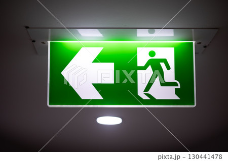 Exit way arrow direction guidance sign green color light emergency exit sign in a dark room Exit way arrow direction guidance sign green color light emergency exit sign in a dark room 130441478
