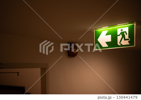 Exit way arrow direction guidance sign green color light emergency exit sign in a dark room 130441479