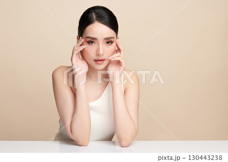 A beautiful young Asian woman with clean, fresh skin against a beige background. Skincare, facial treatment, cosmetology, beauty, and spa. An elegant portrait of an Asian woman. A beautiful young Asian woman with clean, fresh skin against a beige background. Skincare, facial treatment, cosmetology, beauty, and spa. An elegant portrait of an Asian woman. 130443238