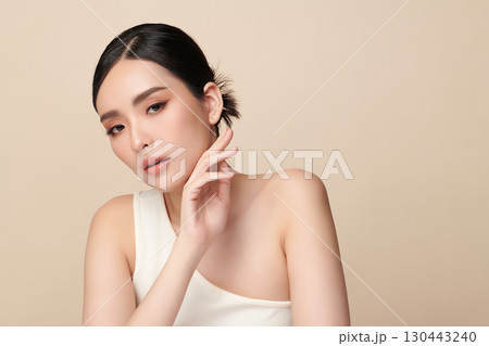 A beautiful young Asian woman with clean, fresh skin against a beige background. Skincare, facial treatment, cosmetology, beauty, and spa. An elegant portrait of an Asian woman. A beautiful young Asian woman with clean, fresh skin against a beige background. Skincare, facial treatment, cosmetology, beauty, and spa. An elegant portrait of an Asian woman. 130443240