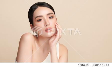 A beautiful young Asian woman with clean, fresh skin against a beige background. Skincare, facial treatment, cosmetology, beauty, and spa. An elegant portrait of an Asian woman. A beautiful young Asian woman with clean, fresh skin against a beige background. Skincare, facial treatment, cosmetology, beauty, and spa. An elegant portrait of an Asian woman. 130443243