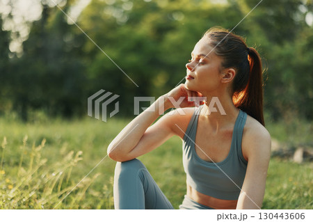 Young woman in athletic wear enjoying nature, exuding calmness and tranquility in a green outdoor setting during a sunny day Young woman in athletic wear enjoying nature, exuding calmness and tranquility in a green outdoor setting during a sunny day 130443606