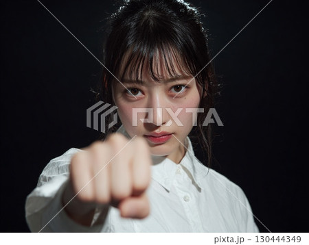 力強く拳を突き出す女性｜強さ、闘い、決意のイメージ 130444349