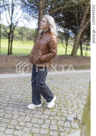 Senior woman walking in park enjoying sunny day Senior woman walking in park enjoying sunny day 130444502
