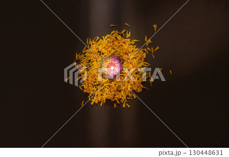 Diwali candle surrounded by vibrant marigold petals 130448631