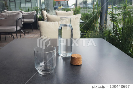 Refreshing water served in a glass and carafe at a modern cafe setting in daylight Refreshing water served in a glass and carafe at a modern cafe setting in daylight 130448697