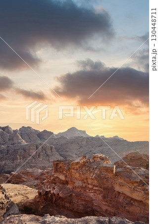 Sunset over rugged mountains showcasing dramatic rock formations and vibrant sky. Petra, jordan. Sunset over rugged mountains showcasing dramatic rock formations and vibrant sky. Petra, jordan. 130448711