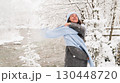 Woman enjoys winter joyfully while wrapped in a blue scarf amidst snowy nature 130448720