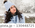 Woman enjoying winter snowfall while wrapped in warmth and happiness during Christmas season 130448725