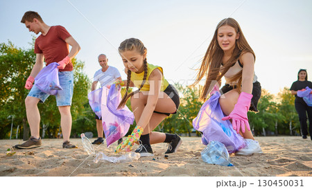 Family with children cleaning sandy beach from plastic trash together 130450031