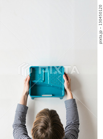 Empty turquoise tray held by person, minimalistic kitchen scene 130450120