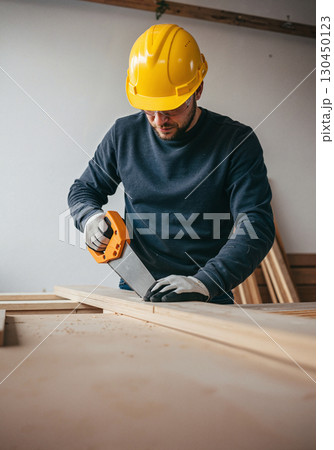 Focused carpenter cutting wood indoors, craftsmanship in action Focused carpenter cutting wood indoors, craftsmanship in action 130450123