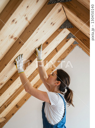 Focused woman working on wooden beams in bright room, home improvement Focused woman working on wooden beams in bright room, home improvement 130450140