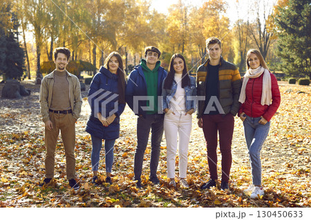 Group of a young happy smiling friends walking in the autumn park. 130450633